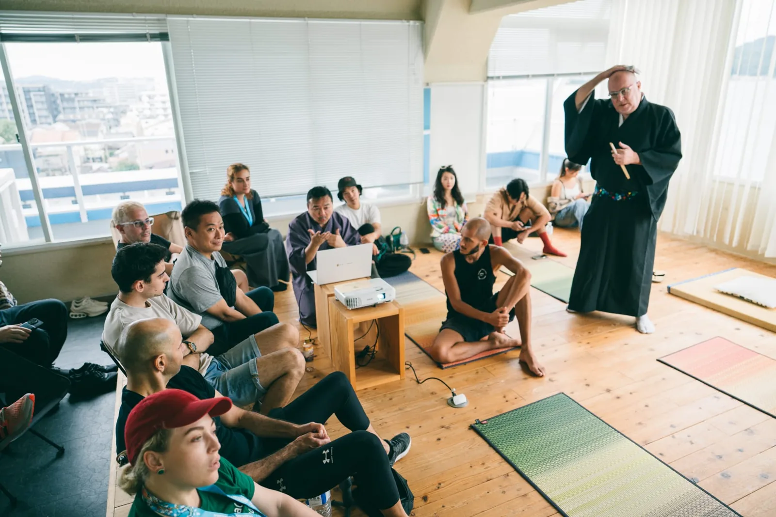 Participants seated on tatami mats during a presentation in a traditional Japanese room.