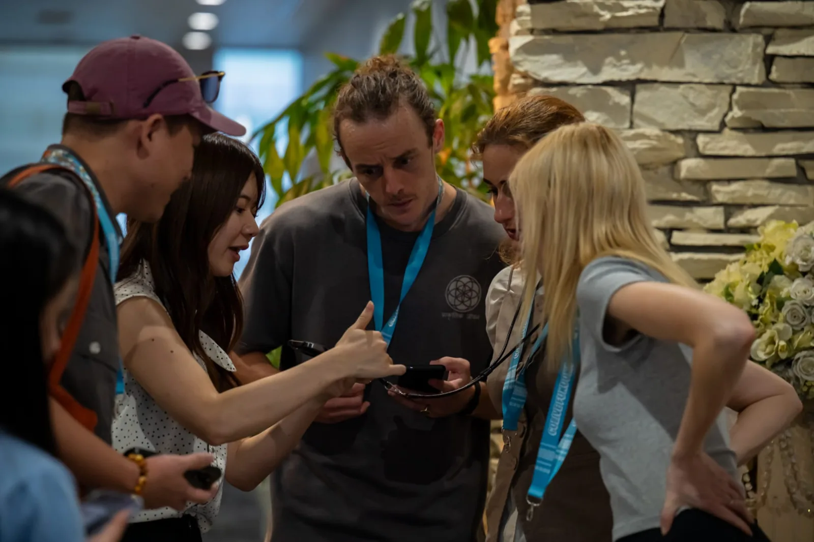 A group of Colive Fukuoka participants huddled around a smartphone during a networking moment.