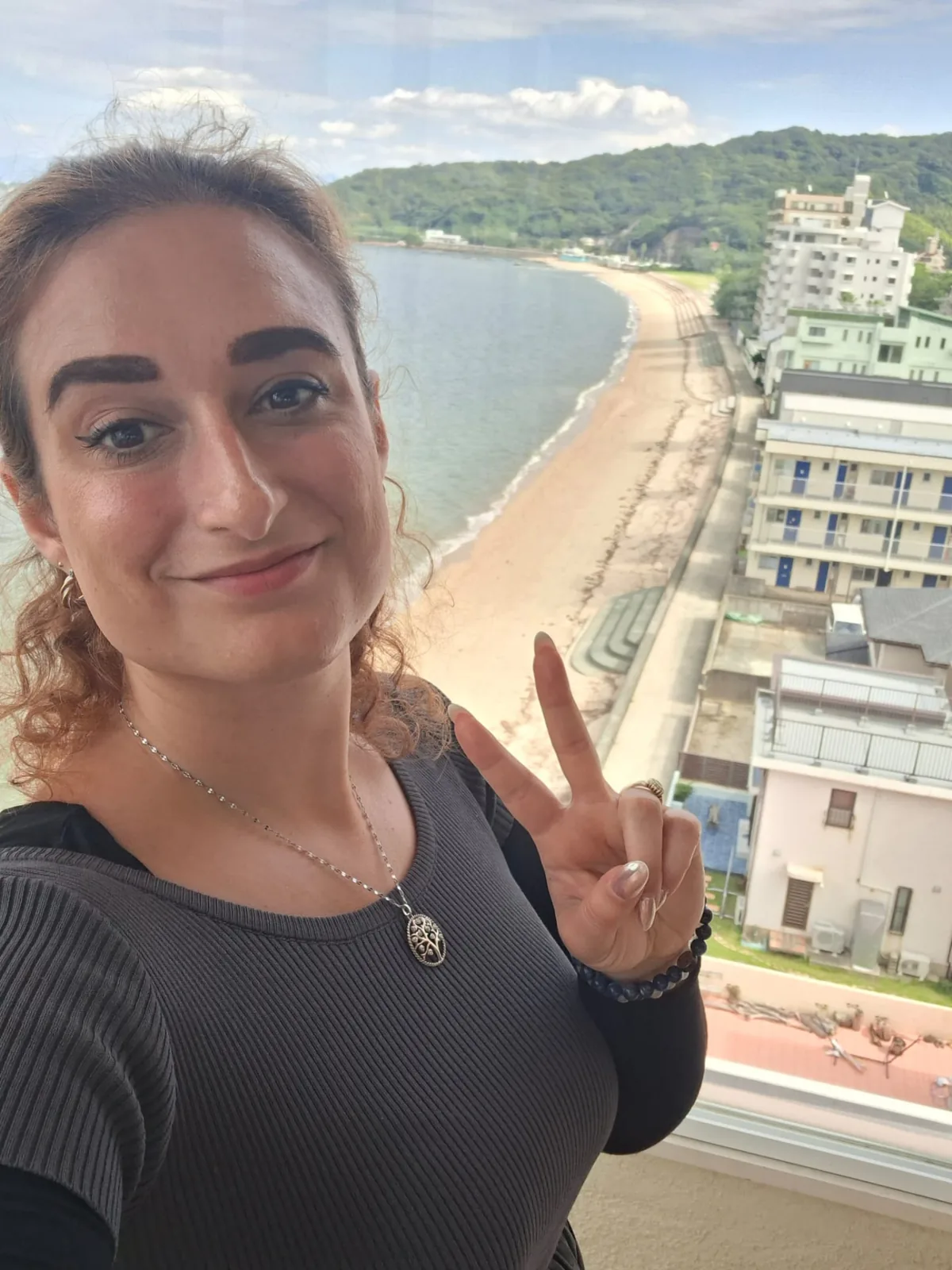 Mirela Curiman on a balcony overlooking the bay and beach in Fukuoka, Japan.